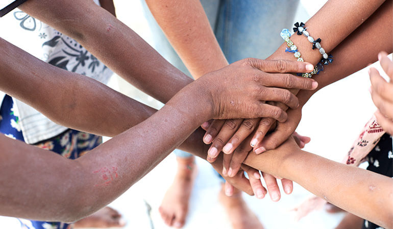 Una vista dall’alto di un gruppo di persone multietniche che uniscono le mani.